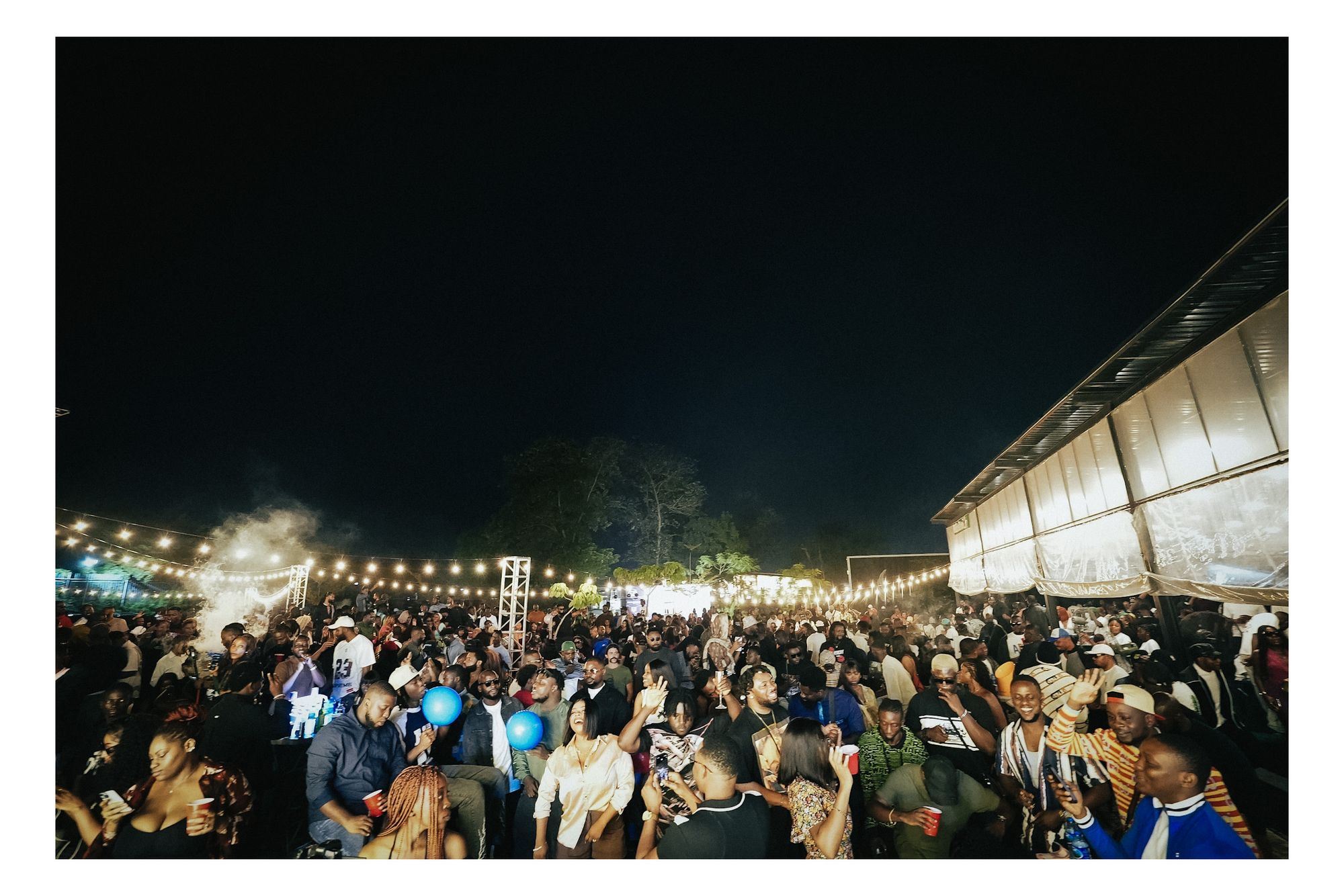 Wide shot of the crowd at Romie's Block under string lights at night